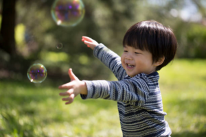 Toddler boy playing outside with bubbles
