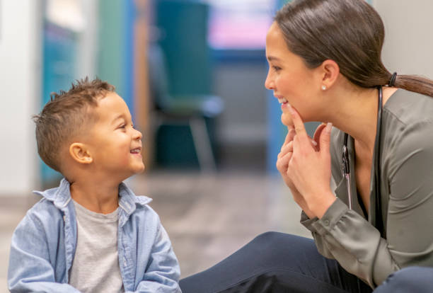 Speech therapist pointing at mouth while working 1 on 1 with young boy during a speech session