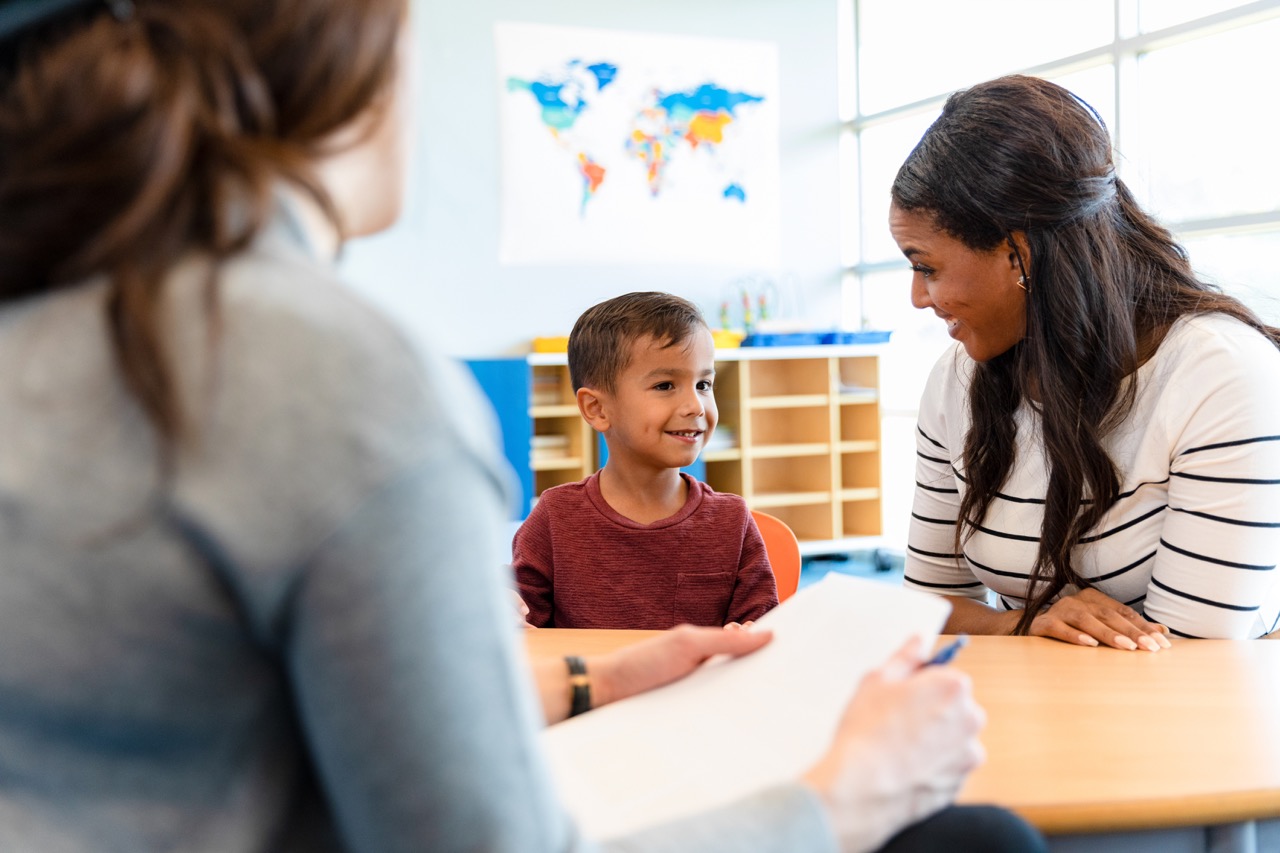 A child psychologist talks with a boy and his mom during a play therapy appointment.