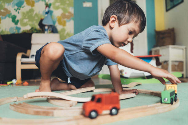 Young boy plays independently with toys cars on the floor