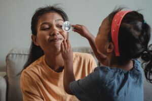 Young girl putting a magnifying glass up to her mothers eye as they play together