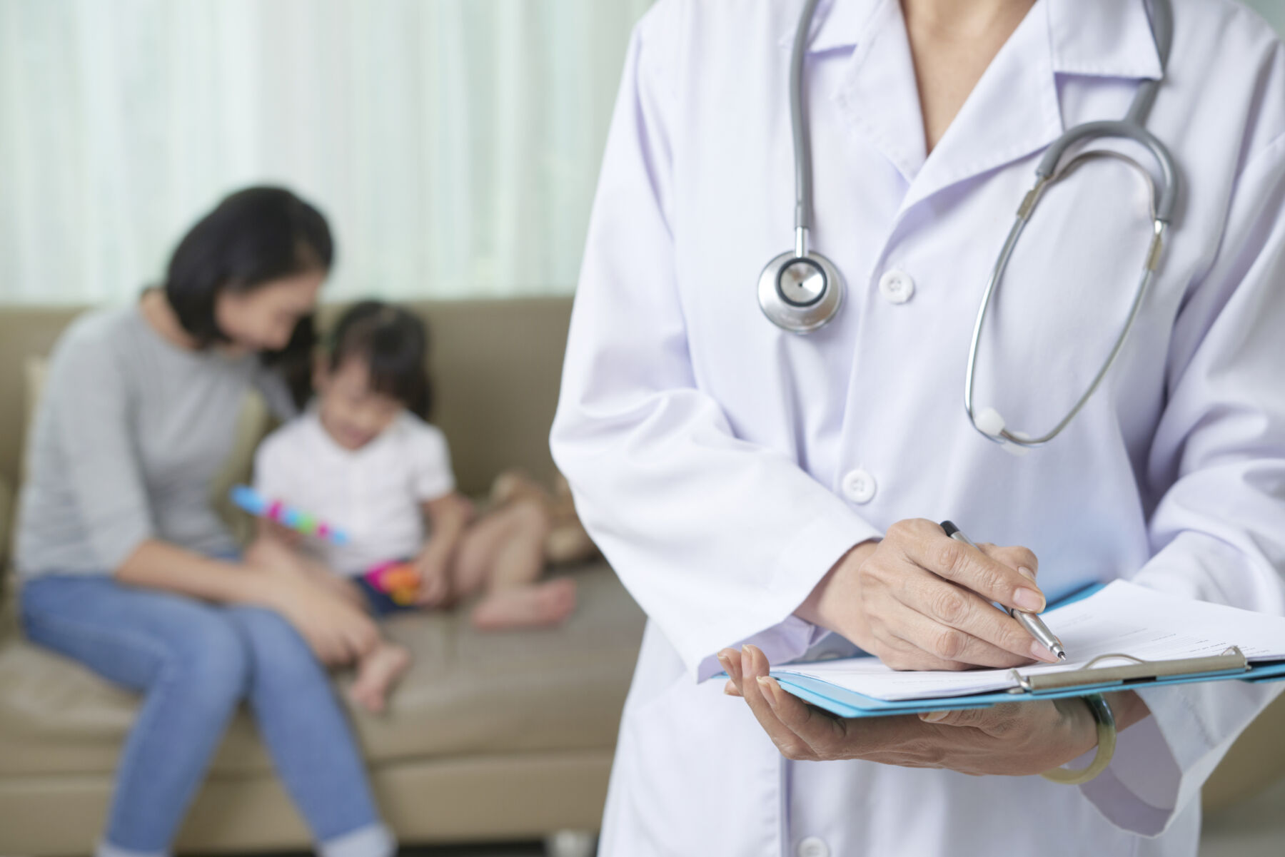 Cropped image of doctor filling medical history of little girl