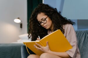 Young curly haired woman sitting while looking at a journal