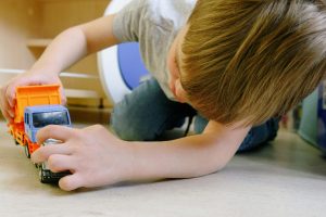 A young boy with autism playing with toys independently.